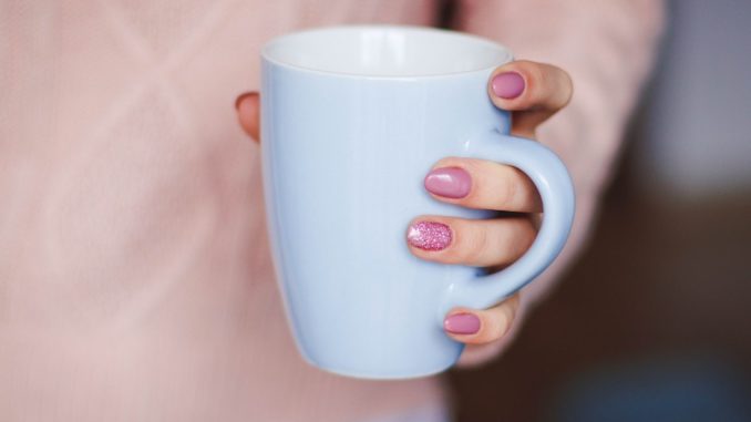 une femme tient une tasse avec une belle manucure